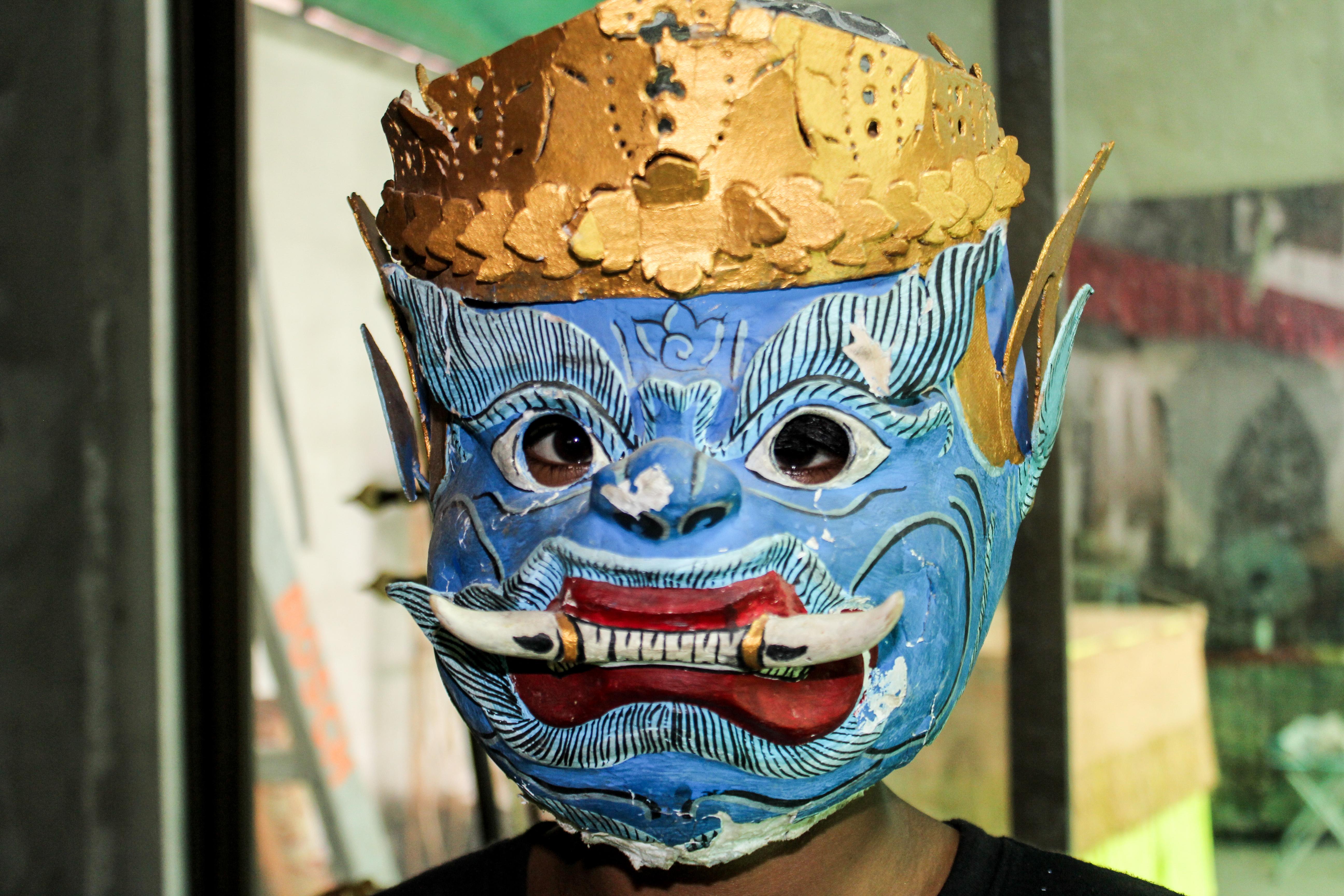 A senior Projects Abroad volunteer wears a traditional mask as part of the Khmer cultural experience in Cambodia. A volunteer over 50 learning about the Khmer culture in Cambodia, wears a traditional mask.
